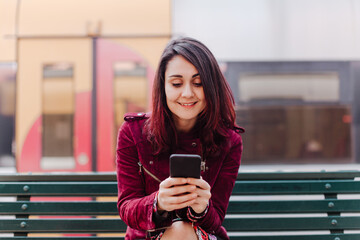 close up of beautiful caucasian woman in train station ready to travel using mobile phone. Travel and lifestyle concept