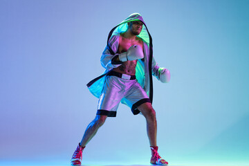 High-fashion styled man in white outfit pacticing box isolted over gradient background in neon light