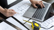 © Puwasit Inyavileart - Young man with a laptop plotting a system of building structures in blueprints, Architects or engineers are designing buildings using computers to calculate the physical structure to be correct.