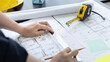 © Puwasit Inyavileart - Architectural building design and construction plans with blueprints, Young man was designing a building or architecture with a ruler, pen, pencil, tape measure, architect hat.