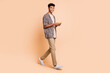 © deagreez - Full size profile portrait of handsome dark skin guy walking look camera have good mood isolated on beige color background