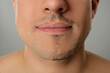 Man with half shaved face on grey background, closeup