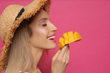 Poster - Young woman with fresh mango on pink background. Exotic fruit