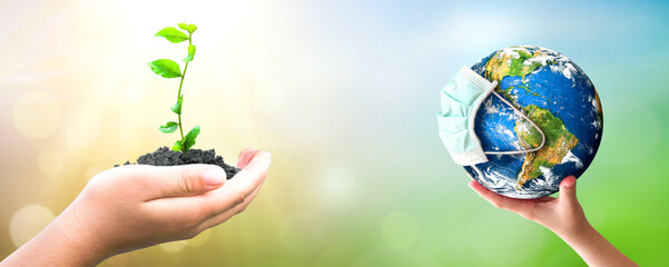 earth day concept: hand holding plant and earth on blur green nature background