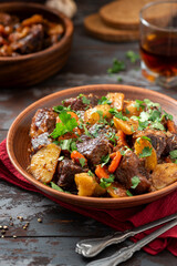 Wall Mural - Goulash. Beef stew with potatoes, onions, carrots and spices in a ceramic plate on a dark wooden table. Rustic style. Stewed meat with vegetables.