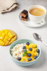 Wall Mural - Cottage cheese with mango pieces and blueberries in a bowl on the table. Healthy breakfast