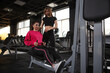© Ihor - Personal trainer and her client using seated cable row gym machine, copy space