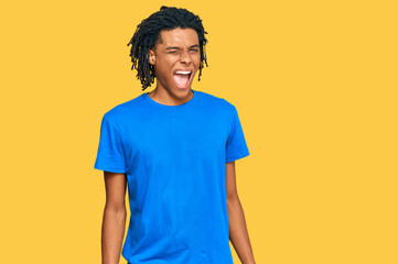 Wall Mural - Young african american man wearing casual clothes winking looking at the camera with sexy expression, cheerful and happy face.