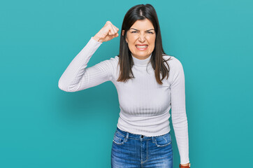 Wall Mural - Beautiful brunette woman wearing casual clothes angry and mad raising fist frustrated and furious while shouting with anger. rage and aggressive concept.