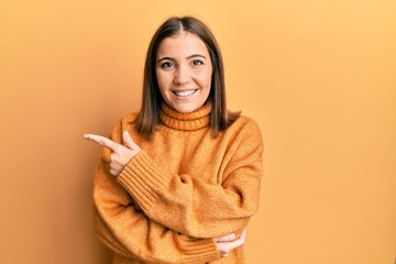 Sticker - Young beautiful woman wearing turtleneck sweater smiling cheerful pointing with hand and finger up to the side