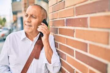 Wall Mural - senior grey-haired businessman smiling happy talking on the smartphone at the city.