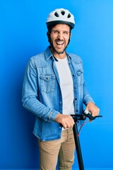 Poster - Young handsome man standing on modern scooter wearing helmet smiling and laughing hard out loud because funny crazy joke.