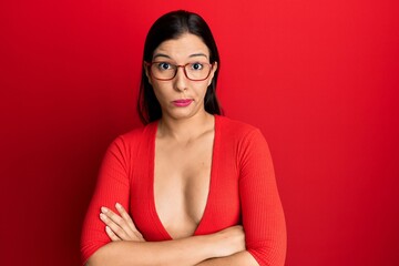 Poster - Young latin woman wearing casual clothes and glasses skeptic and nervous, disapproving expression on face with crossed arms. negative person.