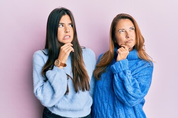 Wall Mural - Hispanic family of mother and daughter wearing wool winter sweater thinking worried about a question, concerned and nervous with hand on chin