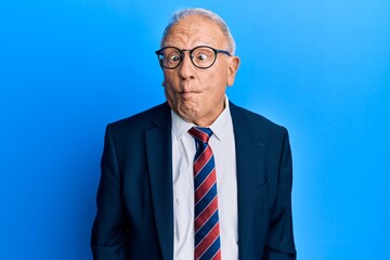 Canvas Print - Senior caucasian man wearing business suit and tie making fish face with lips, crazy and comical gesture. funny expression.