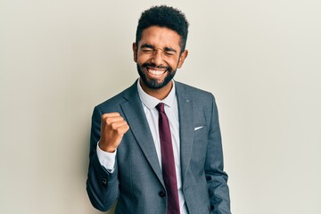 Canvas Print - Handsome hispanic man with beard wearing business suit and tie celebrating surprised and amazed for success with arms raised and eyes closed. winner concept.