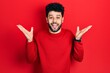 © Krakenimages.com - Young arab man with beard wearing casual red sweater celebrating crazy and amazed for success with arms raised and open eyes screaming excited. winner concept