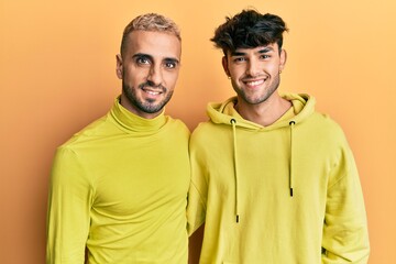 Canvas Print - Homosexual gay couple standing together wearing yellow clothes with a happy and cool smile on face. lucky person.