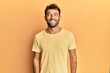 © Krakenimages.com - Handsome man with beard wearing casual yellow tshirt over yellow background with a happy and cool smile on face. lucky person.