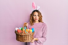 Young Caucasian Woman Wearing Cute Easter Bunny Ears Holding Colored Egg Smiling Looking To The Side And Staring Away Thinking.