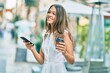 © Krakenimages.com - Beautiful latin teenager girl using smartphone and drinking coffee at the city.