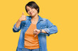 Young beautiful hispanic woman with short hair wearing casual denim jacket doing thumbs up and down, disagreement and agreement expression. crazy conflict