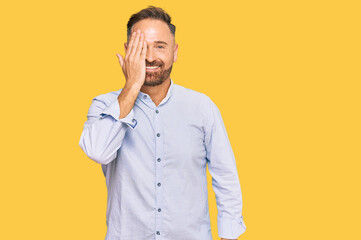 Sticker - Handsome middle age man wearing business shirt covering one eye with hand, confident smile on face and surprise emotion.