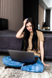 © dianagrytsku - Exhausted woman sit on floor in living room prepare for exam or test suffer from fatigue, tired young ethnic woman study on laptop at home feel overwhelmed, overwork concept