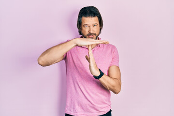 Middle age caucasian man wearing casual white t shirt doing time out gesture with hands, frustrated and serious face