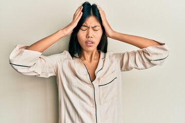 Poster - Young chinese woman wearing pajama suffering from headache desperate and stressed because pain and migraine. hands on head.