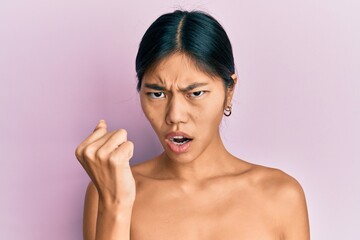 Canvas Print - Young chinese woman standing topless showing skin angry and mad raising fist frustrated and furious while shouting with anger. rage and aggressive concept.