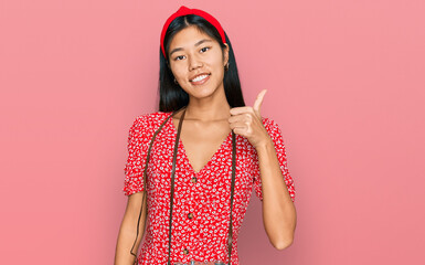 Poster - Beautiful young asian woman wearing dress and vintage camera smiling happy and positive, thumb up doing excellent and approval sign