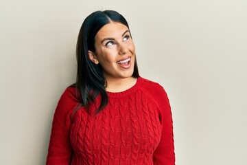 Poster - Beautiful brunette woman wearing wool winter sweater looking away to side with smile on face, natural expression. laughing confident.