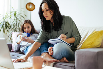 single mother working from home with preteen daughter around