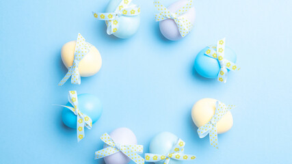 Wall Mural - Easter banner. Colourful egg with tape ribbon on pastel blue background in Happy Easter decoration. Foil minimalist egg design, modern top view template.