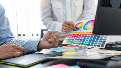 Poster - graphic designer team working on web design using color swatches editing artwork using tablet and a 