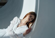 © SHOTPRIME STUDIO - Red-haired Woman in a white dress In a bright room side view and a falling shadow