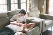 © dodotone - Young adult asian lover couple sitting on sofa cozy style indoor on day.