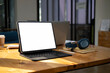 © Prathankarnpap - Mock up computer tablet with white screen, head phone and notebook on wooden desk.