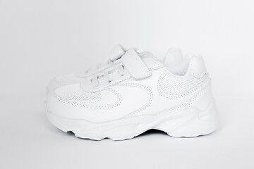 isolated white childrens leather sneakers in a minimalistic style on a white background, concept of childrens shoes 