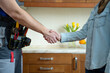 © Grustock - Close up of plumber and client shaking hands in kitchen. Repairman shaking hands with woman