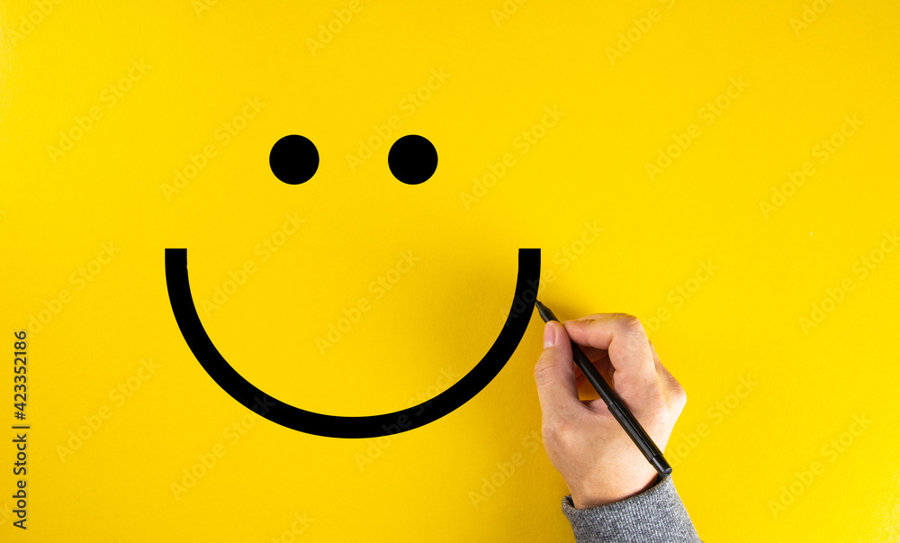 Male hand drawing a smiling happy face sketch on yellow background. Client satisfaction. - obrazy, fototapety, plakaty 