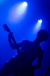 © Damián Basante - Unrecognizable male curly hair guitarrist. Music lights show silhouette during rock band live concert. Foggy light