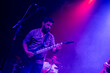 © Damián Basante - Musician playing electric guitar during rock band live concert. Black hair male guitar player performing on stage. Music foggy lights show