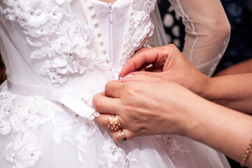 Wall Mural - Bridesmaids tie a bow on the wedding dress. Preparing the bride. Morning of the bride