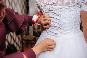 Sticker - Bridesmaids tie a bow on the wedding dress. Preparing the bride. Morning of the bride