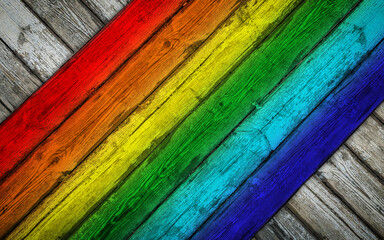 Old white wood plank texture, overlapped at a different angle by old wood planks painted in rainbow colors. The texture of the wood is visible through the cracked and worn paint coat.