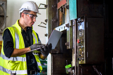 Caucasian engineer mechanic man checking for maintenance pressing metal machine by laptop at factory, worker at industrial concept	