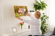 © Angelov - A happy blonde woman is holding a large wall canvas portrait of her family with young children.