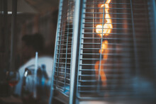 A True Tilt-shift Photo Of A Street Gas Heater For A Patio With A Flame Of Fire Inside, With A Selective Focus On The Part Of A Protective Metal Grid